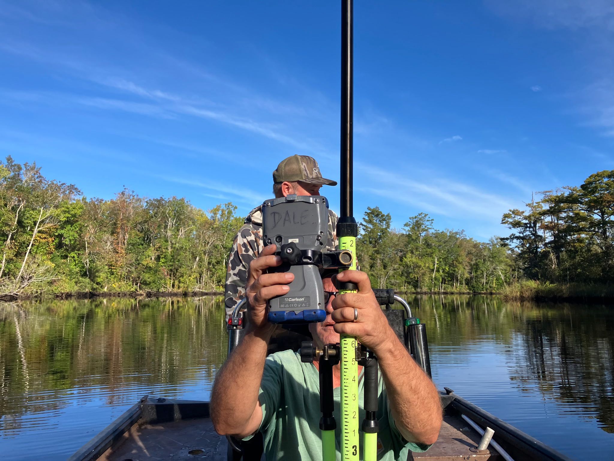 Surveyor with Carlson equipment conducting boundary work on the White Oak River from a boat